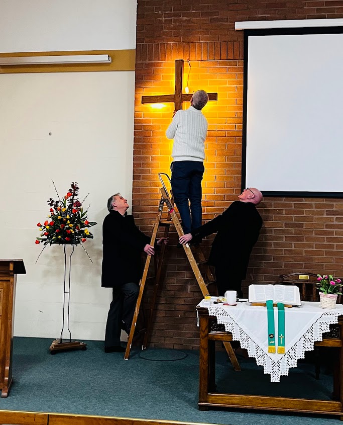 Church Property team and helpers changing a lightbulb in the cross at the front of the church